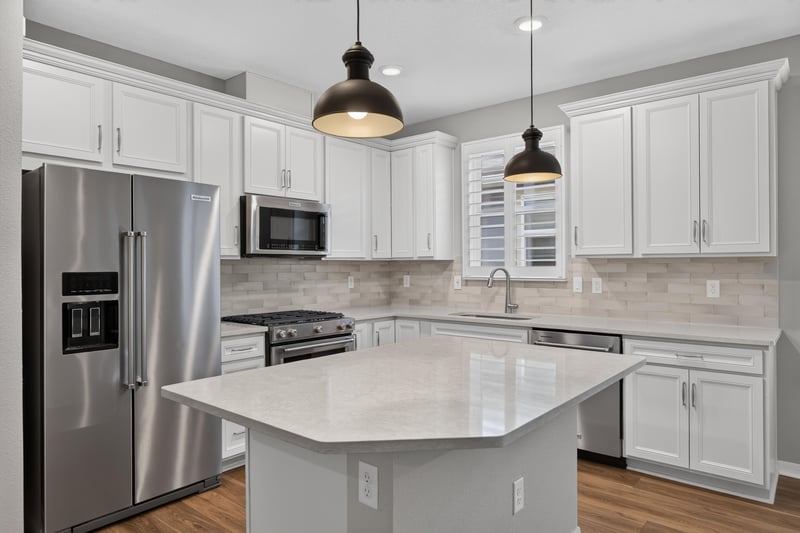 Kitchen island with stainless refrigerator and white cabinets at 171 Oyster Shell Ter, Nocatee, FL 32081