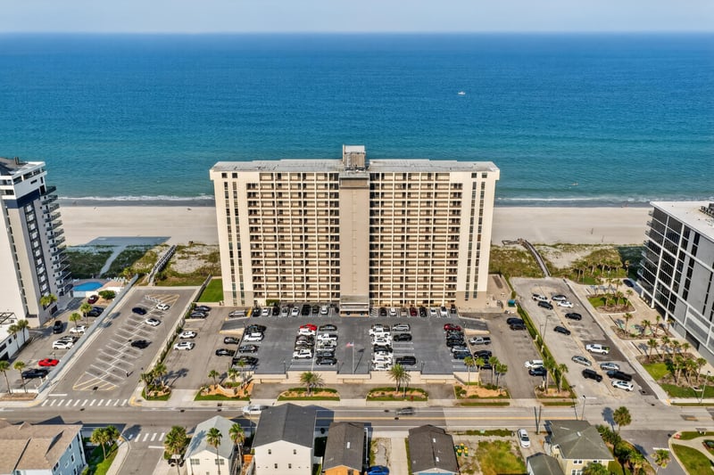 Aerial view of the building front and parking lot by the beach at 1301 1st St S