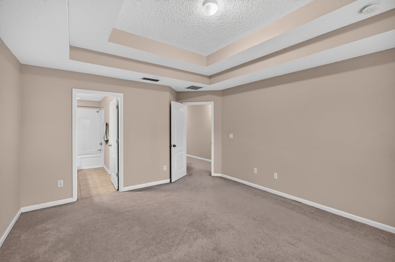 Bedroom with tray ceiling and multiple doors at 3762 Hartsfield Forest Cir, Jacksonville, FL 32277