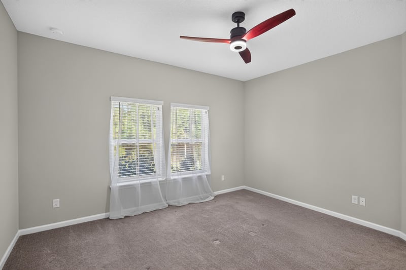 Carpeted bedroom with sheer curtains and ceiling fan at 75875 Saffron Ln, Yulee, FL 32097