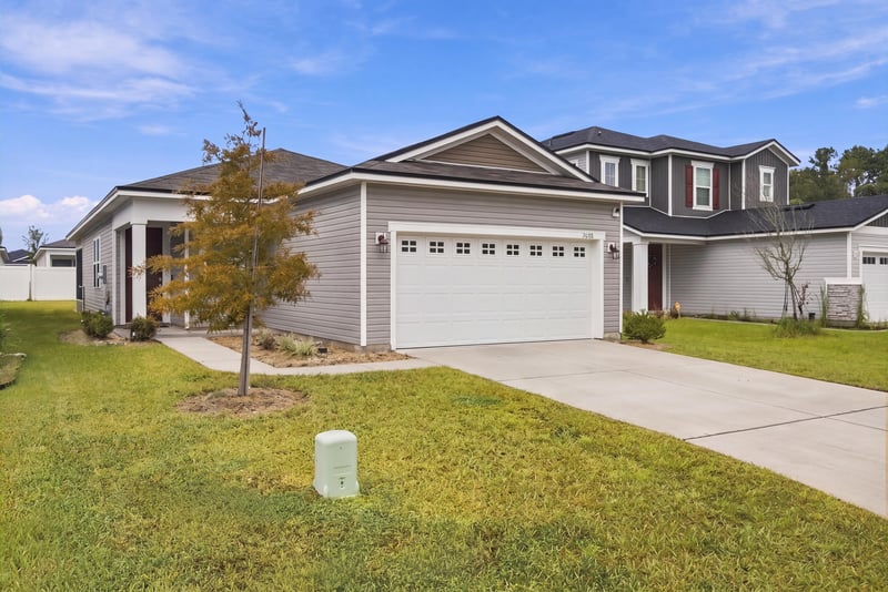 Front exterior with young tree and lawn at 7088 Mahogany Run Dr, Jacksonville, FL 32244