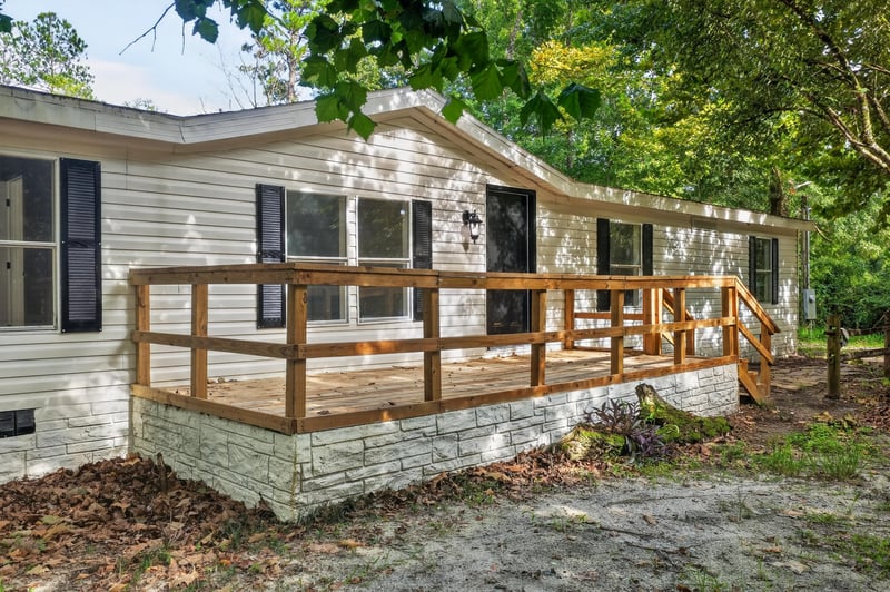 Front exterior with wood deck and stone skirting at 55520 Jewel-Thomas Rd, Callahan, FL 32011