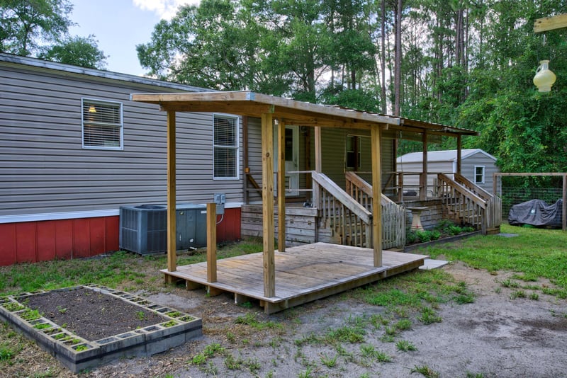 Side exterior with deck stairs and raised garden beds at 2549 Snapdragon Ave, Middleburg, FL 32068