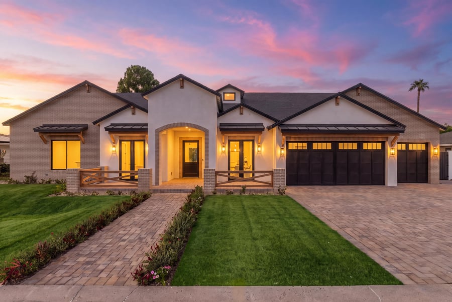 Virtual twilight of a farmhouse-style front with lit windows and a paver walk