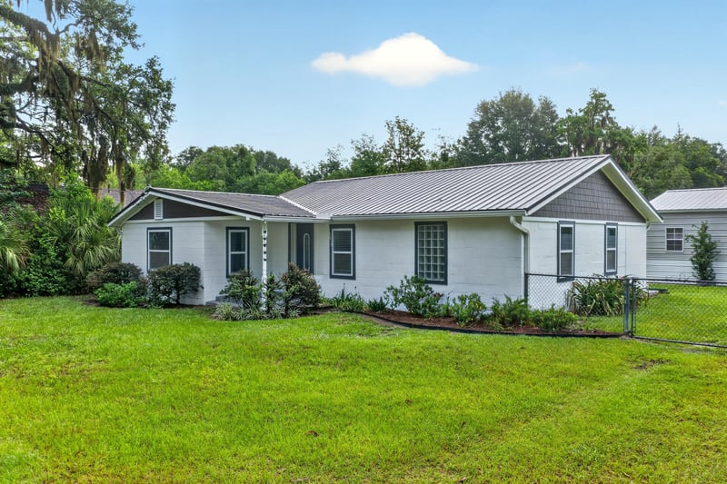 Front exterior in daylight showing white siding and landscaped yard at 1619 Hammond Blvd, Jacksonville, FL