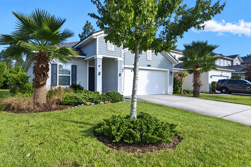 Front exterior with landscaped lawn and palm tree at 75875 Saffron Ln, Yulee, FL 32097
