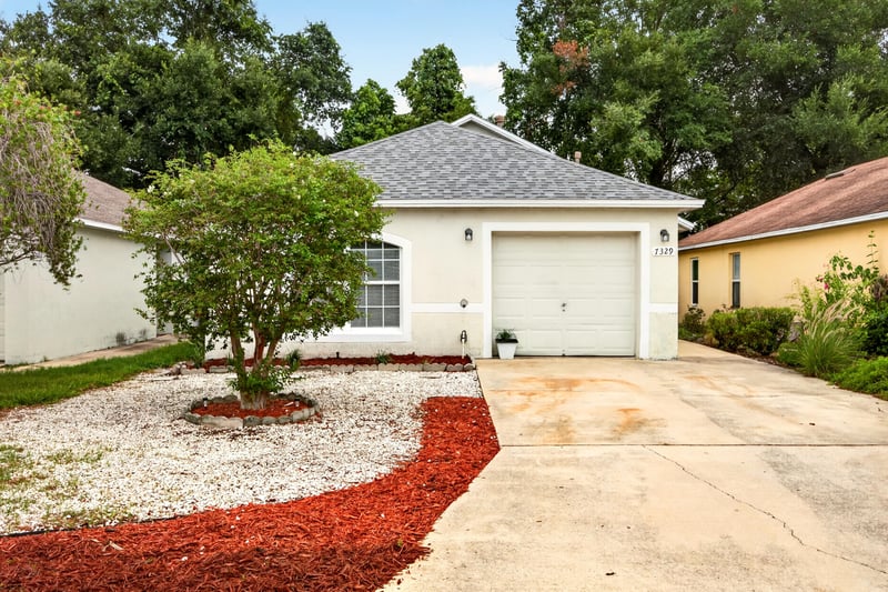Front exterior view with landscaped bed and young tree at 7329 Lawn Tennis Ln, Jacksonville, FL