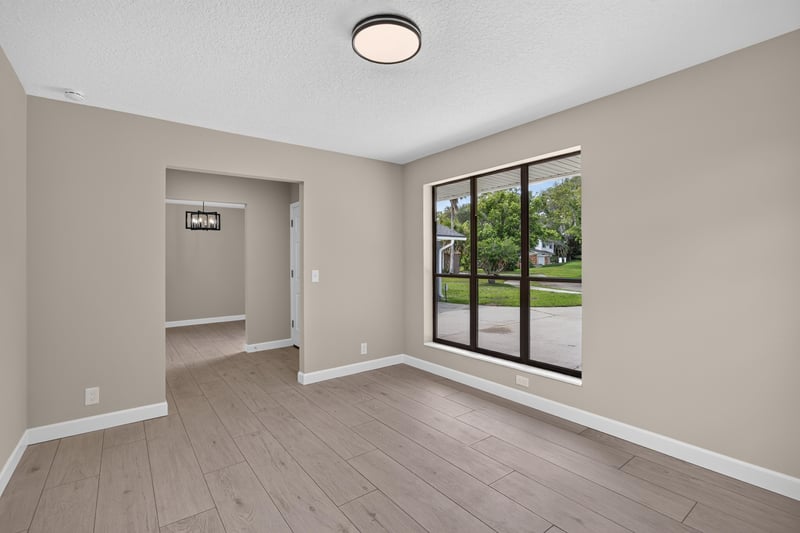 Empty living room with large window and wood-look flooring at 4117 Wilcrest Ct, Jacksonville, FL 32277