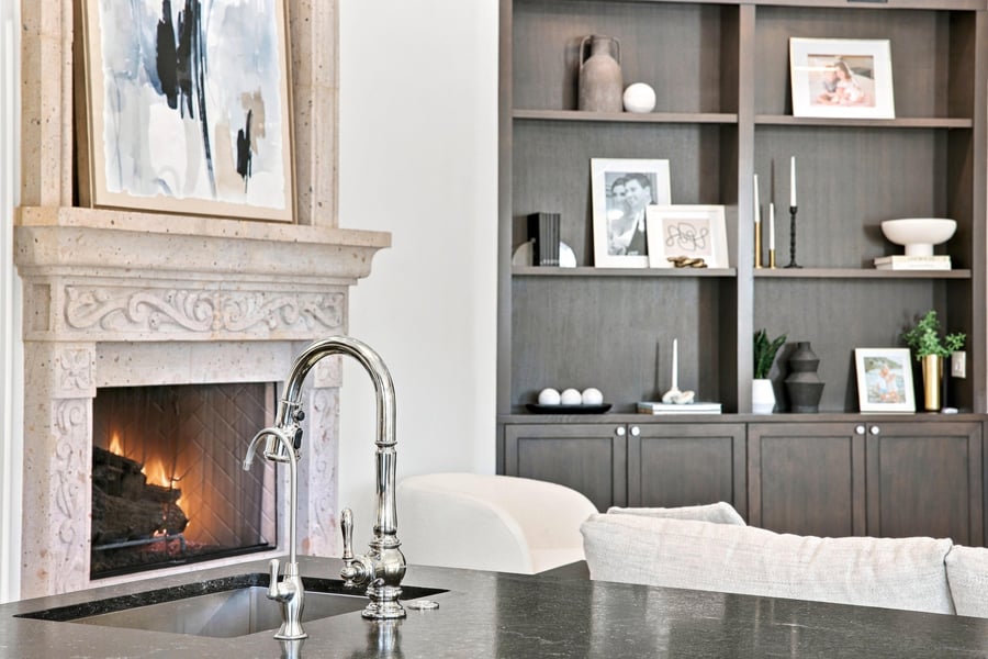 Carved stone fireplace and built-in shelves beside a kitchen sink
