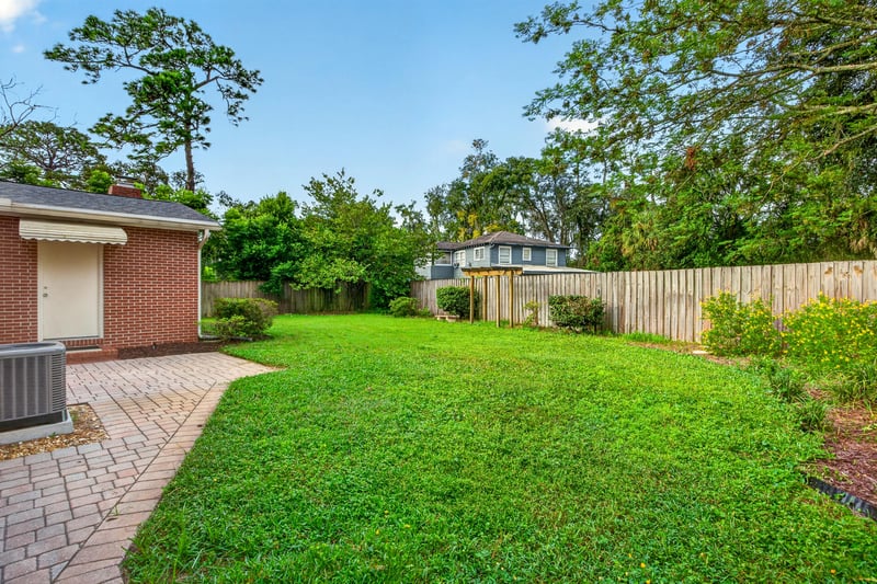 Backyard view with fenced yard and paver walkway at 1834 Memory Ln, Jacksonville, FL