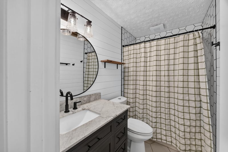 Bathroom vanity with round mirror and black fixtures at 6757 Deer Springs Rd, Keystone Heights, FL 32656