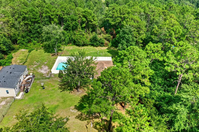 Aerial view of the pool and wooded lot at 2435 Range Line Rd, Middleburg, FL