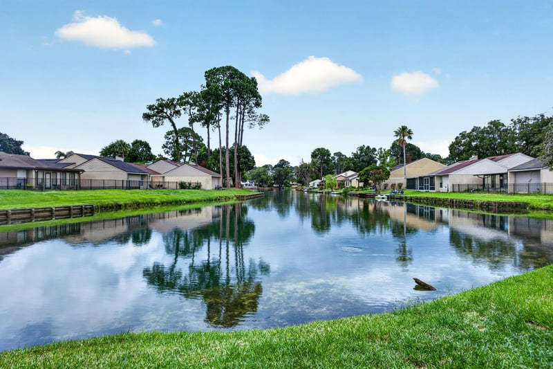 Wide view of community pond with homes in background in Jacksonville, FL