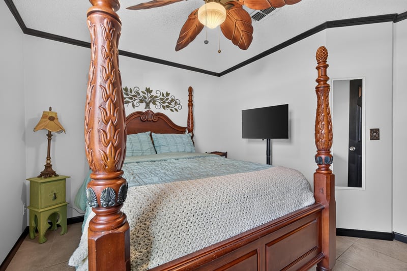 Bedroom with four-poster bed and TV at 6931 Cane Grass Ln E, Jacksonville, FL 32244