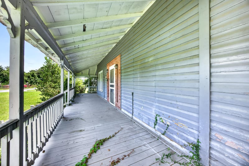 Covered wraparound porch with wood railing at 1173 US-17, Satsuma, FL 32189