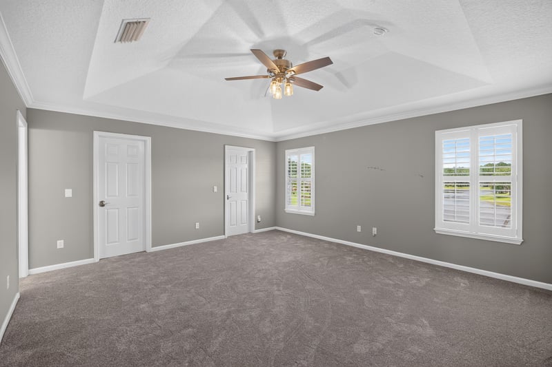 Primary bedroom with tray ceiling and carpet at 1493 Greyfield Dr, St. Augustine, FL 32092