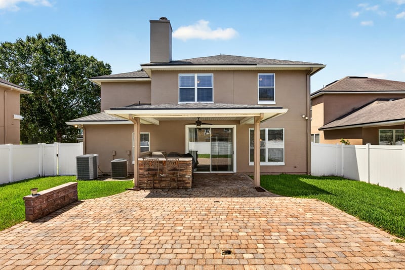 Backyard paver patio enclosed by a white vinyl fence at 3660 Middlebrook Dr, Orange Park, FL 32065