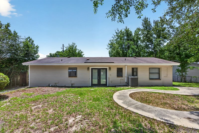 Backyard view with lawn, patio path and trees at 7453 Jade Dr N, Jacksonville, FL 32210