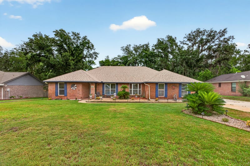 Front exterior of brick ranch home with blue shutters and landscaped lawn at 981 Marble Ridge Dr, Orange Park, FL 32065