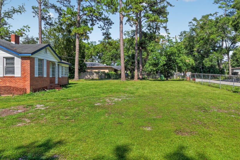 Open side yard bordered by trees at 5745 110th St, Jacksonville, FL 32244