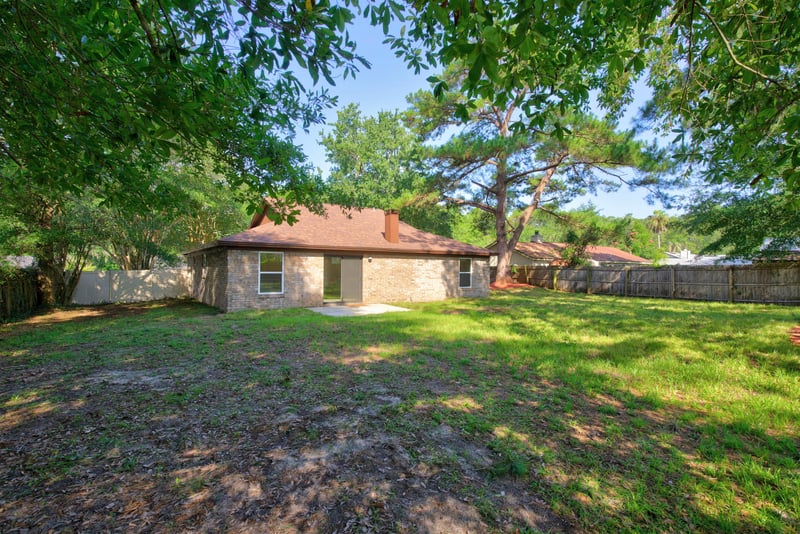 Backyard lawn with fencing and shade trees at 8453 Boysenberry Ln W, Jacksonville, FL