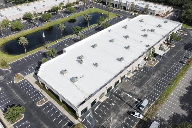 Aerial view of a roofline with pond and palm trees at 10550 Deerwood Park Blvd, Jacksonville, FL 32256