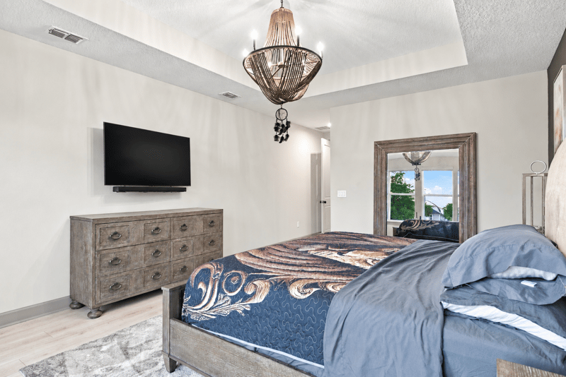 Bedroom with dresser, mirror and mounted TV at 3921 Spyglass Hill Ln