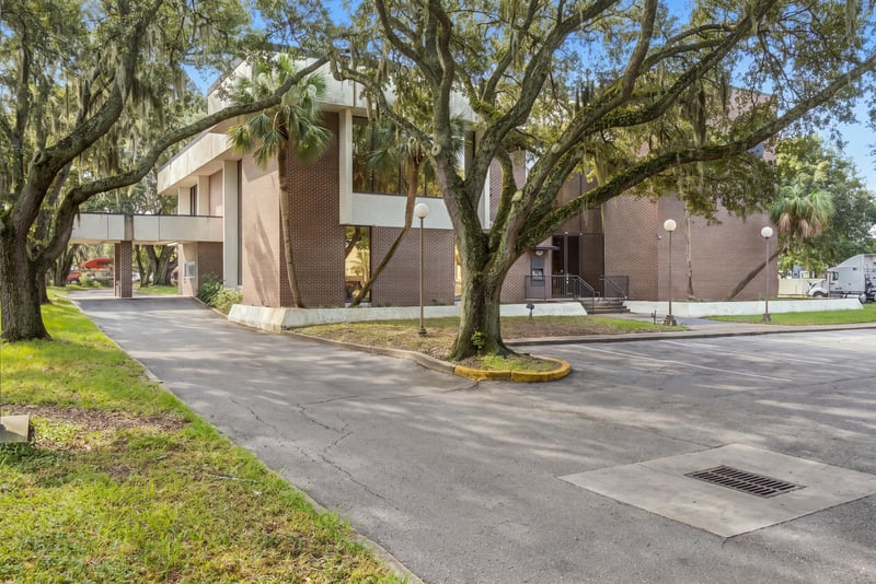 Brick building facade with round window accents under oaks at 101 Scholars Wy