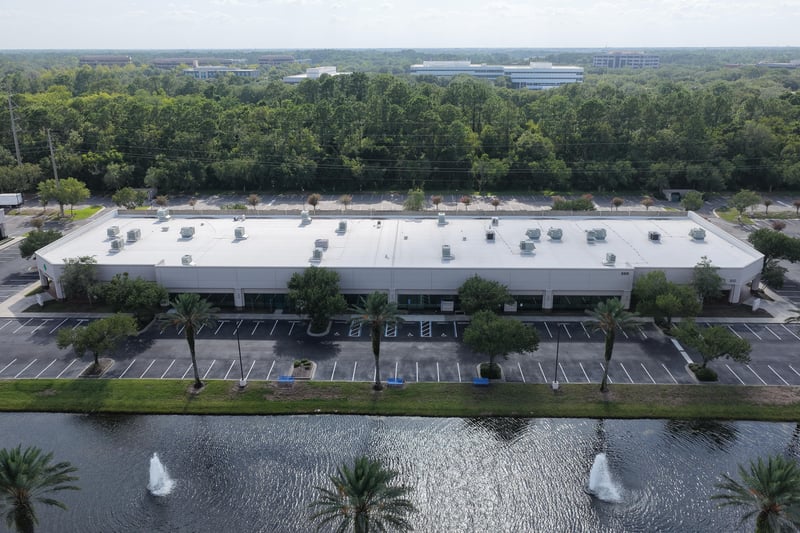 Aerial view of a roofline bordered by trees and open field at 10550 Deerwood Park Blvd, Jacksonville, FL 32256