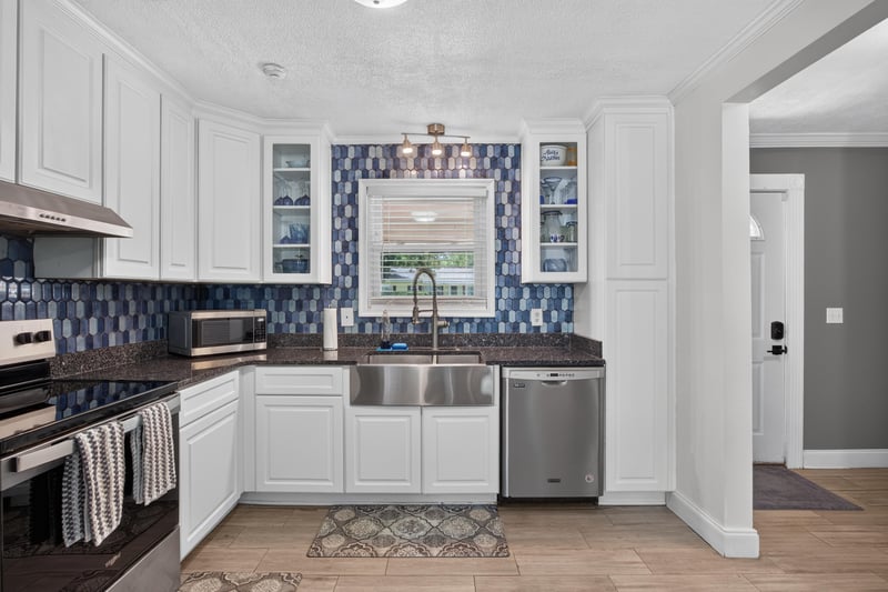 Kitchen sink area with white cabinetry and tile backsplash at 6059 Karen St, Jacksonville, FL 32244