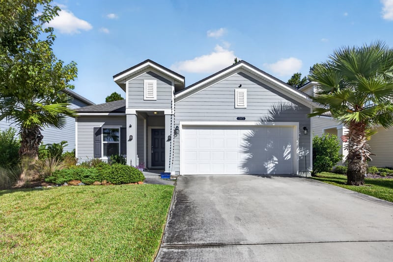 Front exterior with two-car garage and palm trees at 75875 Saffron Ln, Yulee, FL 32097