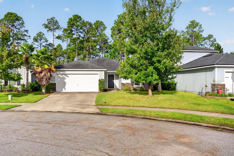Front exterior with driveway and mature trees at 95221 Siena Ct, Fernandina Beach, FL 32034
