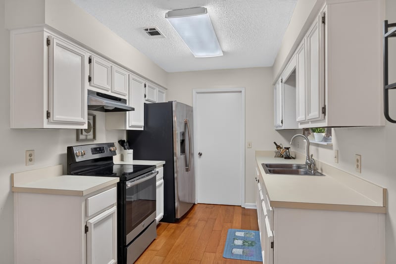 Kitchen with range, white cabinets and center aisle at 2829 Blackberry Ave