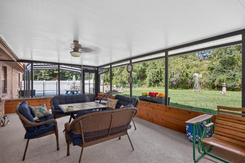 Screened porch with wicker furniture and ceiling fan at 2435 Range Line Rd, Middleburg, FL