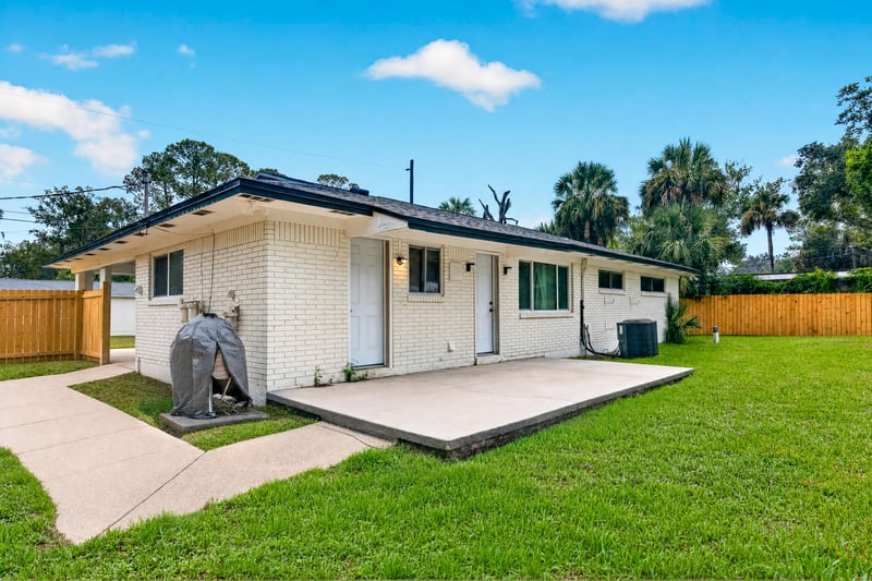 Backyard view of brick home and concrete patio at 9506 Harriet Ave, Jacksonville, FL 32208