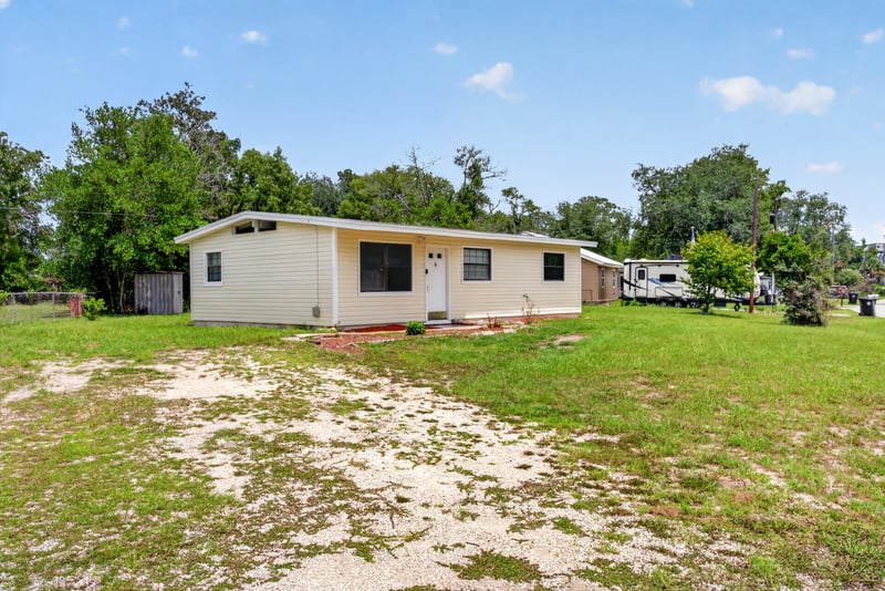 Front exterior with sandy yard patch and trees at 255 Woodside Dr, Orange Park, FL 32073