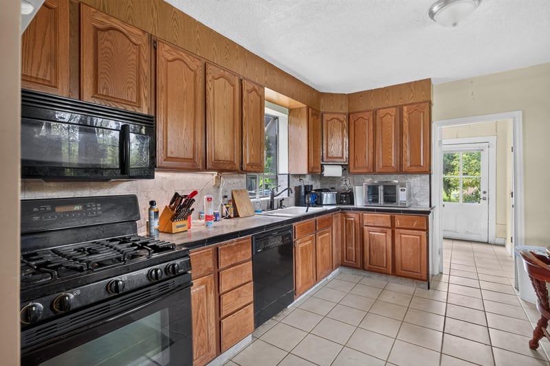 Kitchen with wood cabinets and black appliances at 1173 US-17, Satsuma, FL 32189
