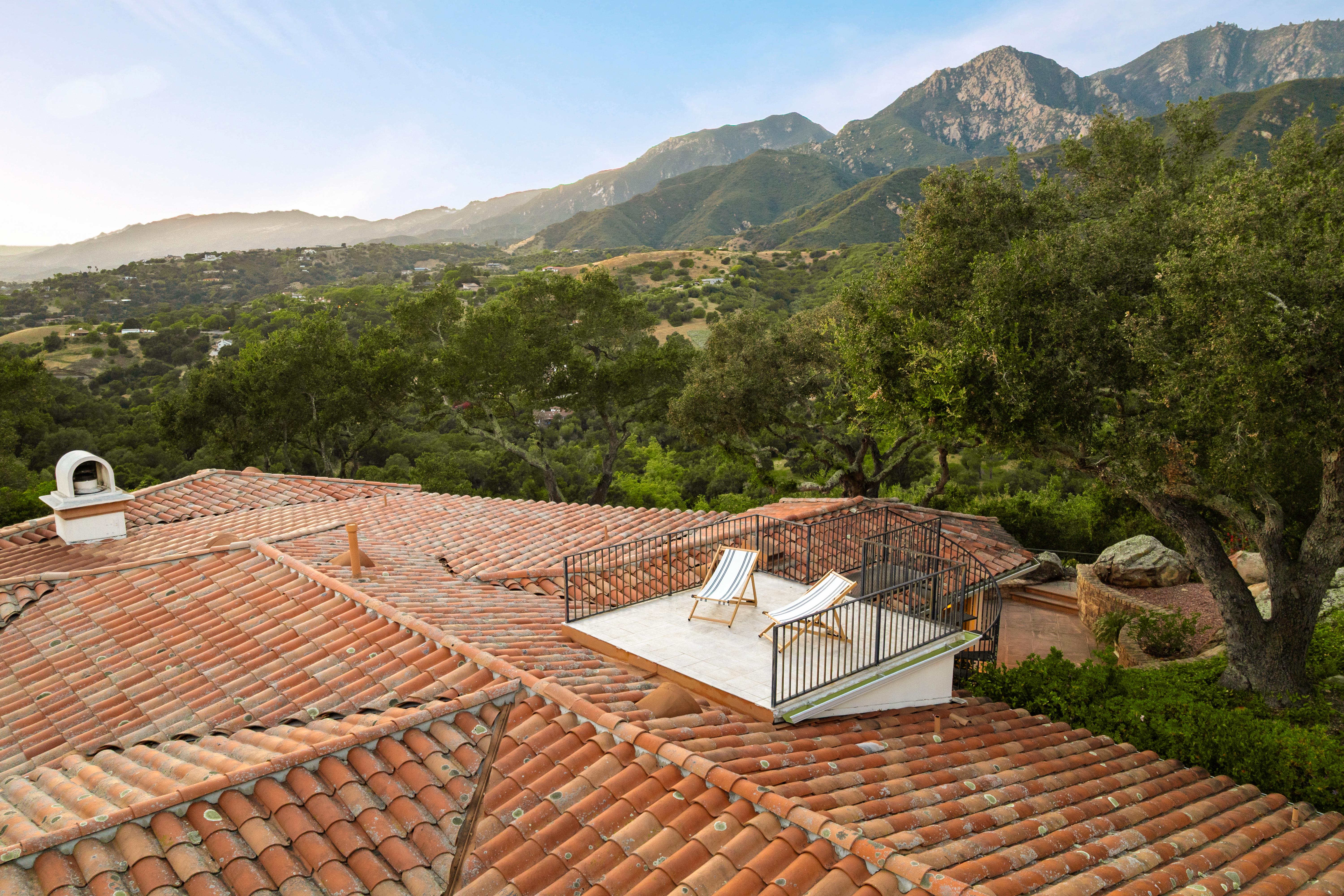 Aerial drone photography of hilltop estate at 450 El Cielito Rd, Santa Barbara — real estate drone photography revealing roofline, mature landscaping, and sweeping Pacific Ocean and Channel Islands panorama above the American Riviera. Our team captured still photography, aerial drone photography, twilight photography, a Matterport virtual tour, a 2D floor plan, and a custom property website from afternoon through twilight.