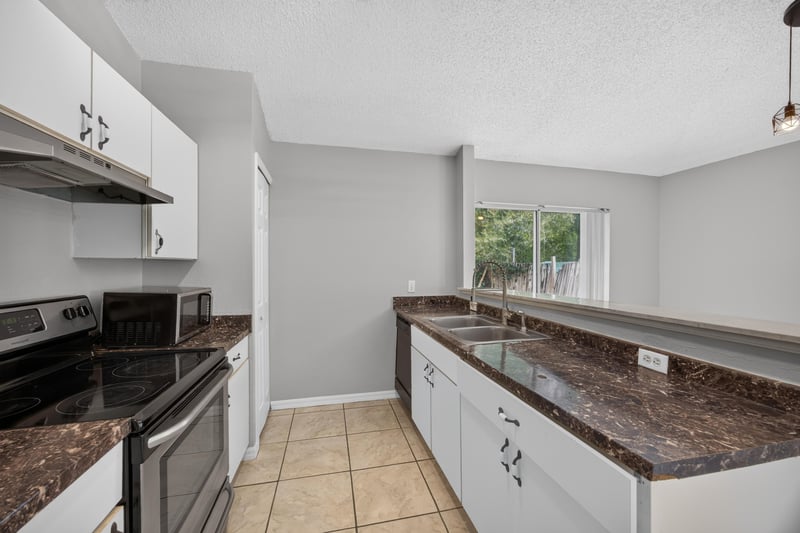 Kitchen counter with granite surface and white cabinets at 7329 Lawn Tennis Ln, Jacksonville, FL