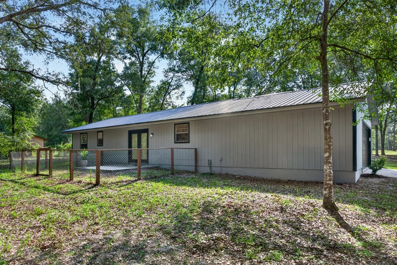 Rear exterior with wooded backdrop and fencing at 2829 Blackberry Ave