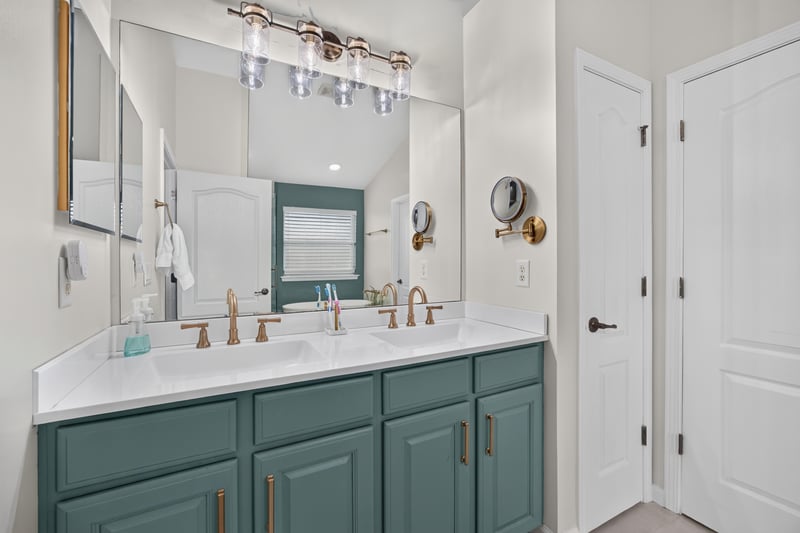 Primary bathroom dual vanity with teal cabinets at 3112 Silverado Cir, Green Cove Springs, FL 32043