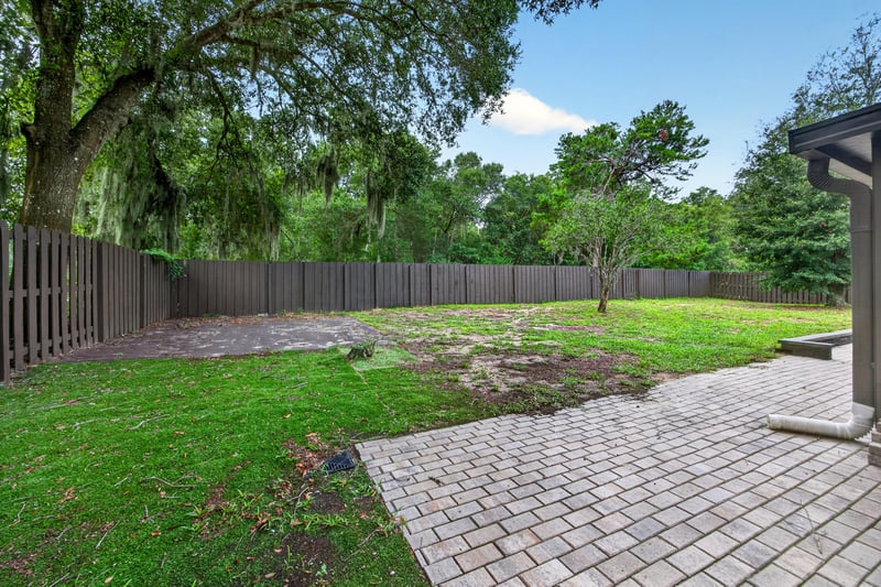 Backyard with grass, fence and paver path at 551 Deltona Blvd, St. Augustine, FL 32086
