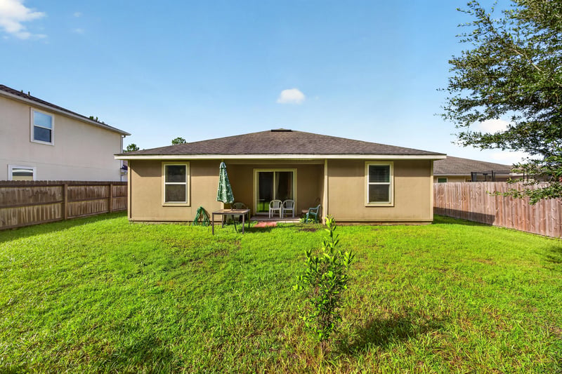 Backyard view of home exterior and fenced lawn at 518 Matecumbe Ct, Macclenny, FL