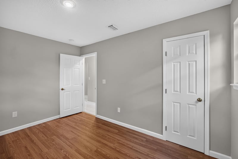 Hallway with closet doors and wood floor at 7015 Miss Muffet Ln N, Jacksonville, FL 32210