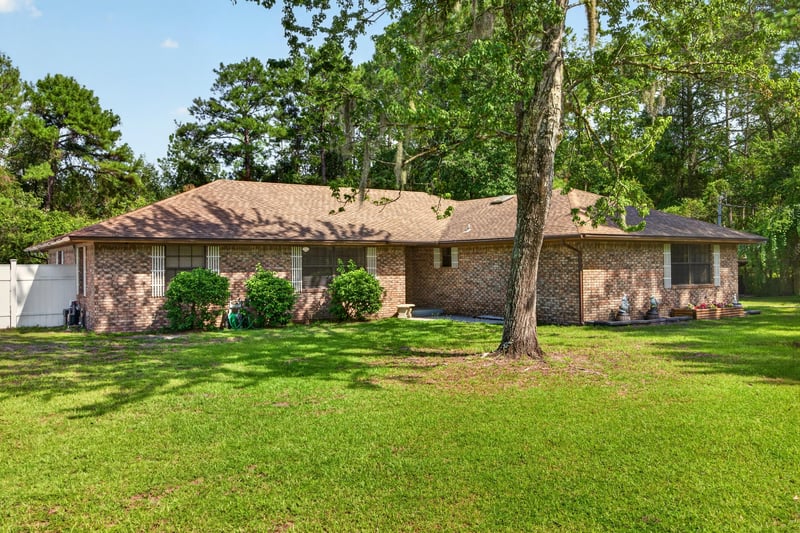 Front exterior of brick ranch home across the front lawn at 2435 Range Line Rd, Middleburg, FL