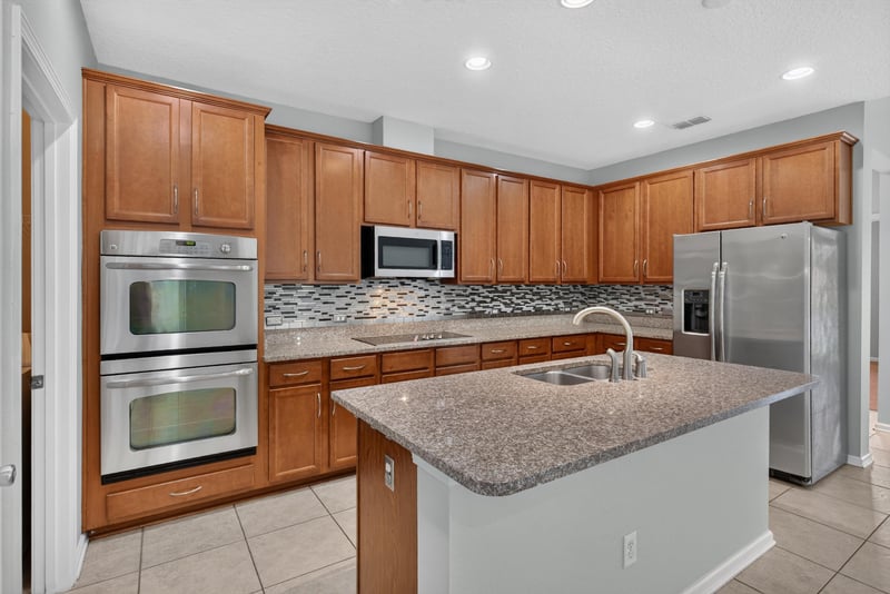 Kitchen with double wall ovens and granite counters at 13685 Goodson Pl, Jacksonville, FL 32226