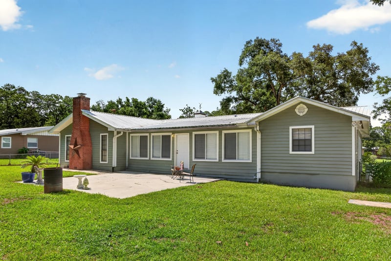 Rear exterior with chimney and covered patio at 5843 Ovella Rd, Jacksonville, FL 32244