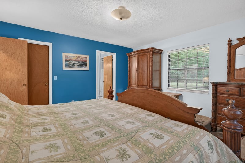 Primary bedroom with wood armoire and bedding at 3249 Maryland Ave, Green Cove Springs, FL