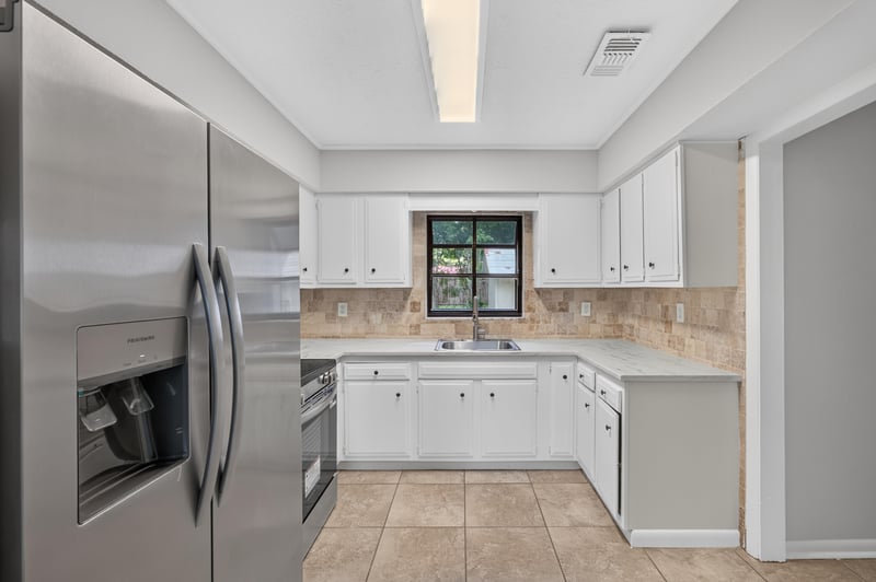 Kitchen view with stainless refrigerator and white cabinets at 7453 Jade Dr N, Jacksonville, FL 32210