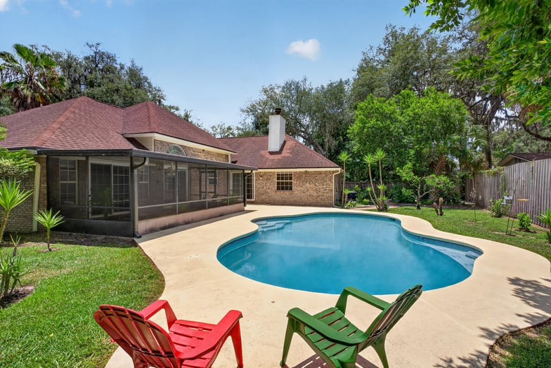 Backyard pool and screened patio with chairs at 12810 Swamp Owl Ln